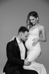 Couple studio intimate portrait. Man hugging his pregnant woman.