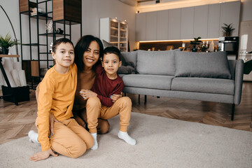 Portrait of happy afro american family in the kitchen, mom and two sons looking at the camera