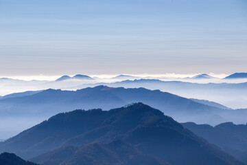 A panoramic view on the mountain peaks of the Hochschwab Region in Upper Styria, Austria. Cloudless weather on a sunny summer day in the Alps. Blue misty valley and soft hills. Concept freedom