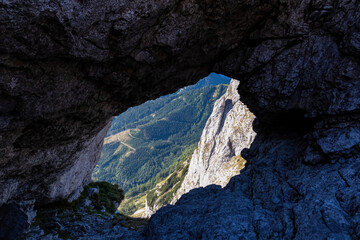 Panoramic view through a rocky hole on the mountain peak Zinken in the Hochschwab Region in Upper Styria, Austria. Massive sharp high rock wall in the Alps in Europe. Cave. Concept freedom. Limestone