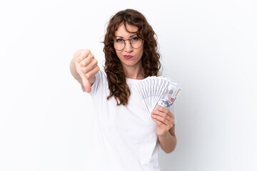 Young woman with curly hair taking a lot of money isolated background on white background showing thumb down with negative expression