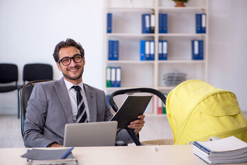 Young male employee looking after new born at workplace