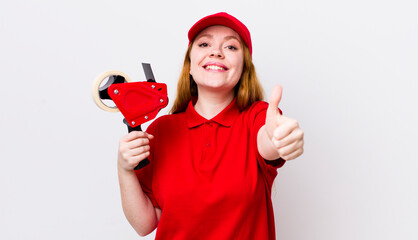 red head pretty woman feeling proud,smiling positively with thumbs up. packer employee concept