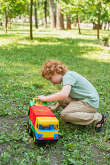 full length view of boy playing with toy truck on green grass.