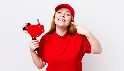 red head pretty woman smiling confidently pointing to own broad smile. packer employee concept