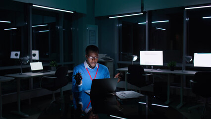 Fototapeta premium African-American businessman having video call on laptop overworking at night