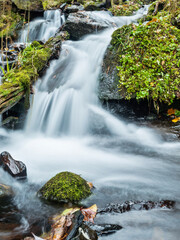 Blurred waterfall throughing mossy rocks