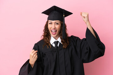 Young university graduate woman isolated on pink background celebrating a victory