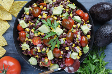 Homemade Mexican black bean and corn salad or Texas caviar bean dip lime dressing, Served with tortilla chips and fresh ingredients. Table top view, flatlay.