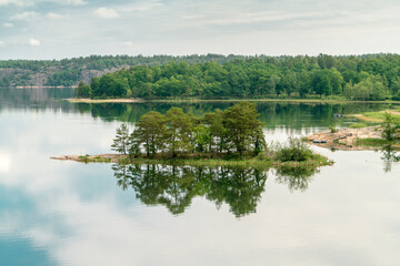 Sweden, Loftahammar, Small island on calm sea trees and clouds © Image Source RF