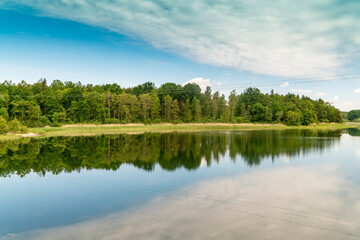 Sweden, Loftahammar, Calm sea surface reflecting trees and clouds © Image Source RF