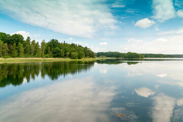 Sweden, Loftahammar, Calm sea surface reflecting trees and clouds