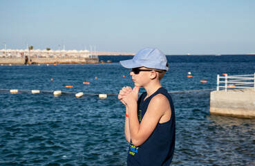 boy teenager walks along the promenade on the pier by the sea