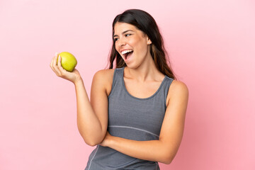 Young caucasian woman isolated on pink background with an apple and happy