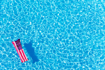 Inflatable mattress with USA flag floating in the pool - obrazy, fototapety, plakaty