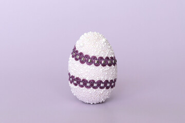 Easter egg decoration on purple background, minimal design with space for text. Side view, close-up