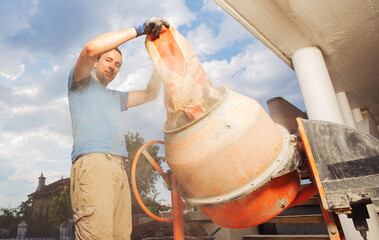 Man adds cement into mixer doing DIY work at home