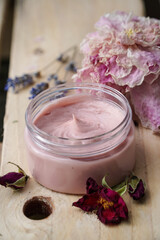 Obraz na płótnie Canvas Homemade pink face or body cream wit lavender and wild rose flowers on the wooden background. 
