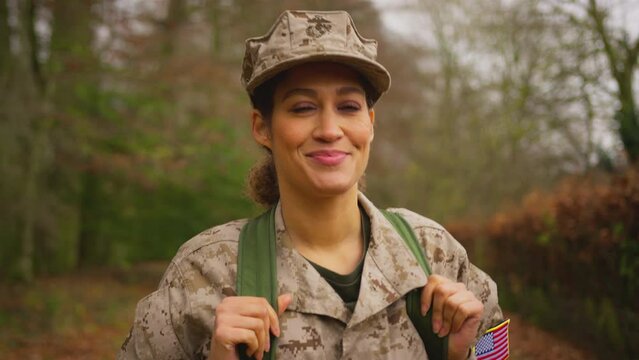 Front view of female soldier in camouflage uniform carrying kit bag walking home to see family on leave - shot in slow motion