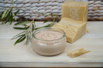   Natural homemade body lotion or face cream with olive oil. Olive branch in the background.  