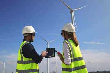 Wind turbine service engineer wearing PPE working on tablet at Wind turbine farm. Wind turbine service engineer wearing PPE working on tablet at Wind turbine farm.