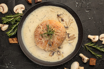Mushroom cream soup in a dark bowl, champignons, bun