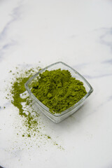 moringa leaf powder in a small bowl among empty white bowls