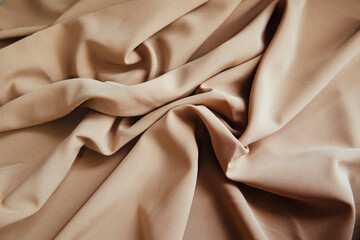 Beige fabric for drapery. A piece of matter with purple folds.