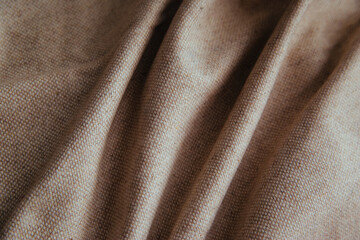 Beige linen fabric for drapery. A piece of cotton with purple folds.