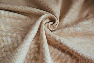 Beige linen fabric for drapery. A piece of cotton with purple folds.