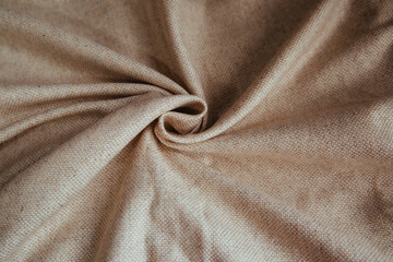 Beige linen fabric for drapery. A piece of cotton with purple folds.