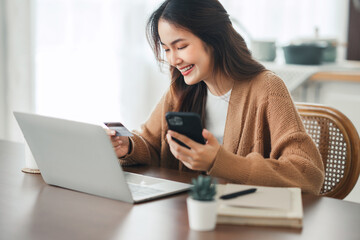 Online payment, Happy asian woman holding a credit card and using smart phone and laptop for online shopping