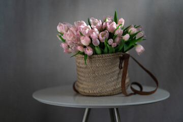 Pink tulips flowers in a basket on the table. Rustic background. Place for text. Selective focus