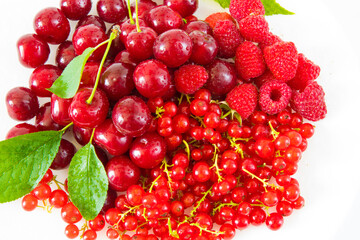 Assorted red fresh berries on a plate on a white background.