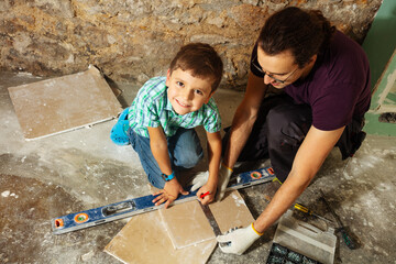 Father with his little boy measure and cut plasterboard