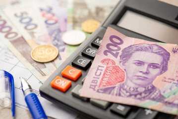 Close up photo of two hundred hryvnia bill on calculator pen utility bills ukrainian hryvnia...