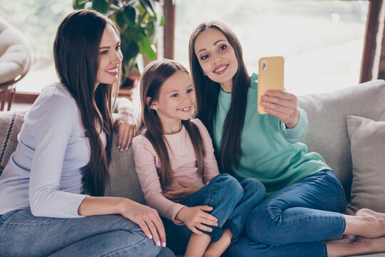 Photo of three charming girl shoot selfie picture speak video call cellphone sitting divan flat indoors