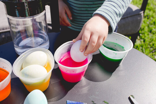 child decorating Easter eggs in the back yard stock photo royalty free