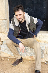 Handsome man with a beard posing on the street. Stylish young man in warm clothes. Hipster in nature on a sunny day.