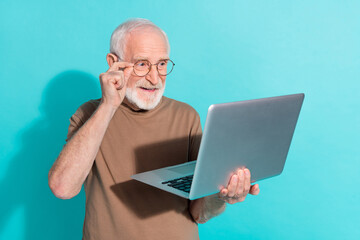 Portrait of attractive skilled grey-haired man using laptop eshop booking order isolated over bright blue color background