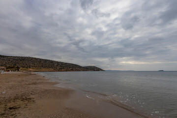 Beautiful seascape with waves, sandy beach and cloudy sky. Aegean Sea