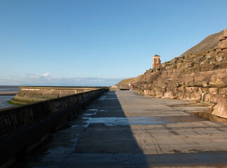 concrete stairs on seawall in the cliffs area blackpool with the beach at low tide in sunlight with the old boat pool and tower in the difference