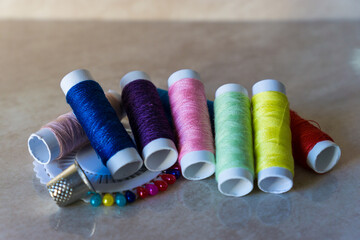 Set of thread spools of various colors with pins and thimble