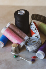 Set of thread spools of various colors with pins, thimble and tape measure