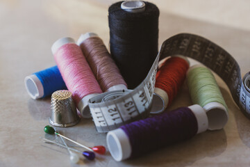 Set of thread spools of various colors with pins, thimble and tape measure