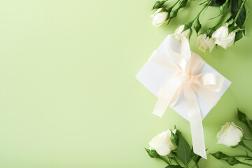 Festive flower composition purple color and white gift box with white ribbon on light green background. Flowers frame. Overhead view. Top view with copy space.