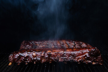 Barbecue ribs cooking on smoker grill - obrazy, fototapety, plakaty