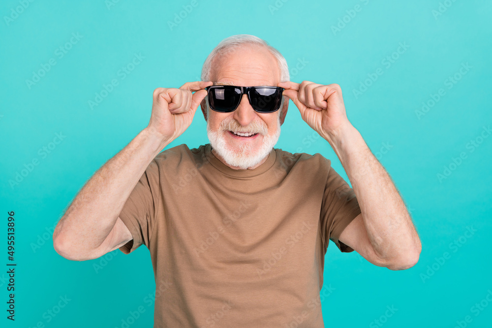 Wall mural Portrait of attractive cheerful funky grey-haired man touching specs good mood isolated over bright blue color background