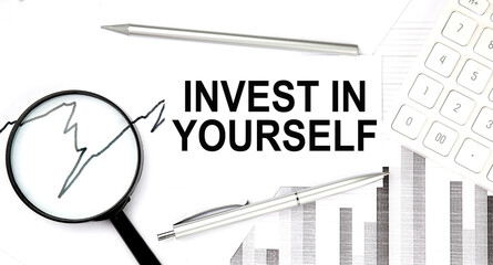 INVEST IN YOURSELF text on document with pen,graph and magnifier,calculator