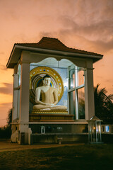 A large white statue of sitting Buddha at sunset, Unawatuna, Sri Lanka. Popular tourist destination.
